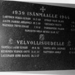 Mustavalkoinen lähikuva tummasta muistolaatasta, jossa on kaiverrettu risti ja tekstiä. Laatta on jaettu kahteen osaan, joiden otsikot ovat "1939 ISÄNMAALLE 1944" ja "VELVOLLISUUDELLE". Otsikoiden alla on lueteltu nimiä syntymäaikoineen ja kuolinpäivineen.