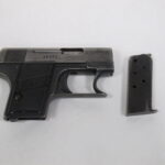 Käsiase ja lipas kuvattuna vaaleaa taustaa vasten.