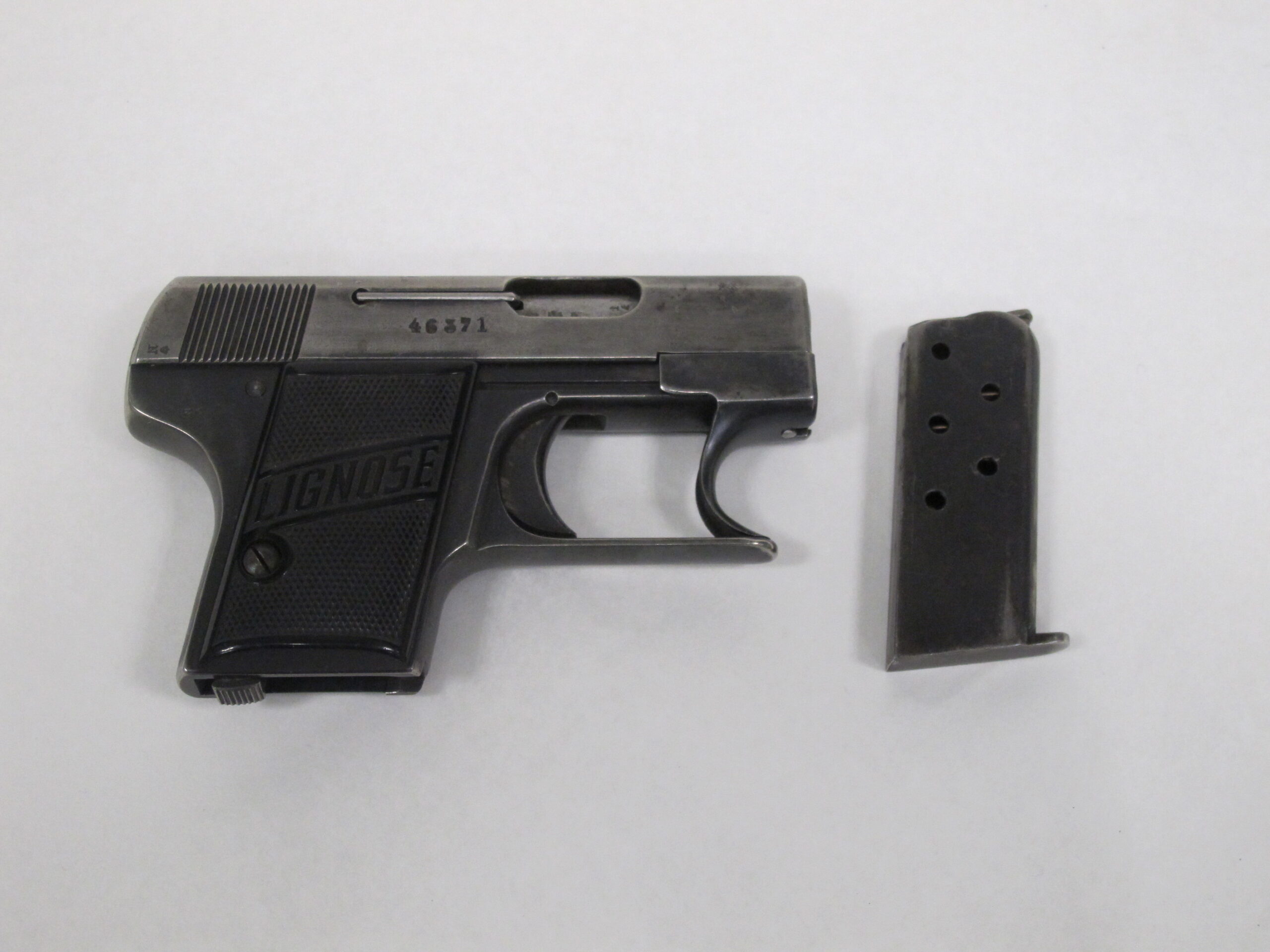 Käsiase ja lipas kuvattuna vaaleaa taustaa vasten.