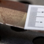 Värikuva, jossa poliisin käyttämä mitta on asetettu todistuskappaleen viereen. Esine metallinvärinen ja siinä on sormenjälki.