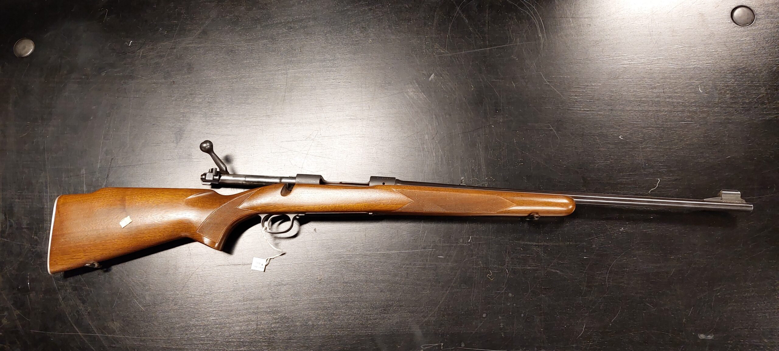 Ylhäältä otettu kuva kivääristä tummaa taustaa vasten.