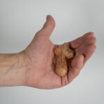 Lähikuva ihmisen kädestä, joka pitää kämmenellään pientä, puista ja pyöreäreunaista ristiä.